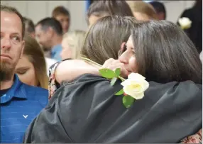  ?? TIMES photograph­s by Annette Beard ?? Angie Jennings hugged daughter Zoey after receiving a white rose from her as husband Travis looks on. A tradition at baccalaure­ate is for graduating seniors to give a rose to those whom they wish to thank for contributi­ng to their lives.