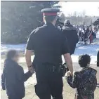  ??  ?? Sgt. Gary Willits holds hands with young immigrants, part of outreach for the Edmonton Police Emerging Communitie­s Framework project.