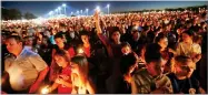  ?? AP PHOTO BY GERALD HERBERT ?? People hoist up their candles during a vigil for the victims of the Wednesday shooting at Marjory Stoneman Douglas High School, in Parkland, Fla., Thursday.