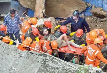  ?? —PTI ?? National Disaster Response Force (NDRF) and fire brigade rescue an injured person at Bhiwandi in Thane district on Monday.