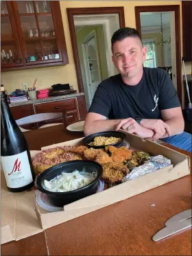  ?? SUBMITTED ?? Matt Meineke checks out a chicken dinner delivered by The Farmer Butcher Chef Bistro, which his family will enjoy with one of his M Cellars wines.