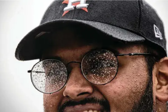  ?? Brett Coomer / Houston Chronicle ?? Water droplets cover Astros fan Aseem Ali’s glasses as he waits for relatives to be evacuated from the flooded Grand Mission subdivisio­n. The team returns home Saturday.