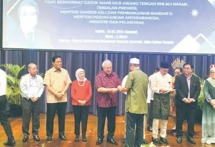  ?? ?? Awang Tengah presents a cheque to one of the landowners. Seen, from his right, are Nancy and Dr Abdul Rahman.