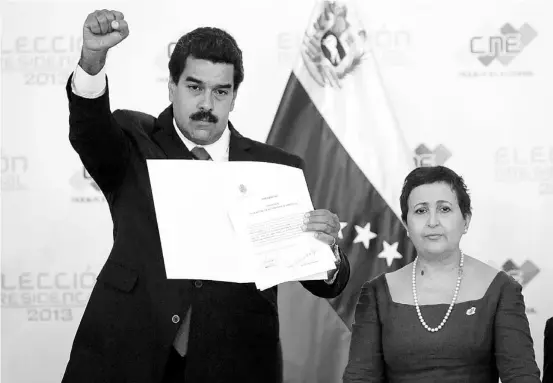  ??  ?? EL GOBERNANTE encargado y candidato del oficialism­o, Nicolás Maduro, saluda tras ser proclamado como presidente de Venezuela ante el Consejo Nacional Electoral, junto a la directora del organismo, Tibisay Lucena.