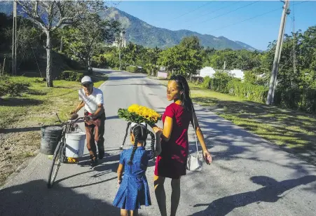  ?? RAMON ESPINOSA, AP ?? Dainet Cala and her daughter Evelyn carry flowers to leave as an offering at the shrine of the Virgin of Charity of Cobre in El Cobre, Cuba. The Vatican-recognized Virgin, venerated by Catholics and followers of Afro-Cuban Santeria traditions, is at the heart of Cuban identity, uniting compatriot­s from the Communist-run Caribbean island to those who were exiled or emigrated to the U.S.