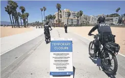  ??  ?? Police officers patrol along the closed and nearly empty Santa Monica beach Friday. LA County beaches reopened Monday.