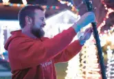  ?? ?? Burns Harbor resident Andy Bozak adjusts a string of lights on an archway across his driveway as he troublesho­ots decoration­s in his yard.