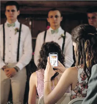  ??  ?? A guest is seen capturing an image on her cellphone at a wedding photograph­ed by Lainie Hird Photograph­y this past May. The company’s owner, Lainie Hanlon, says gadget use during ceremonies has worsened in recent years.