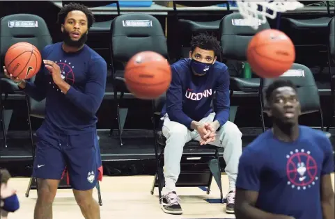  ?? David Butler II / Associated Press ?? UConn’s James Bouknight, middle, looks on from the sideline as his teammates warm up before a game against Butler.