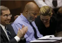  ?? CHRISTIAN GOODEN — ST. LOUIS POST-DISPATCH VIA AP ?? Lamar Johnson, center, and his attorneys react on Tuesday after Circuit Judge David Mason vacated his murder conviction during a hearing in St. Louis, Mo.