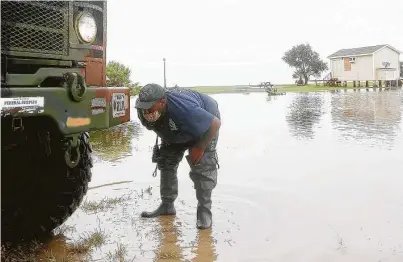  ?? Elizabeth Conley / Staff photograph­er ?? Volunteer firefighte­r William White checks the tires of a high-water rescue vehicle in Smith Point on Tuesday.