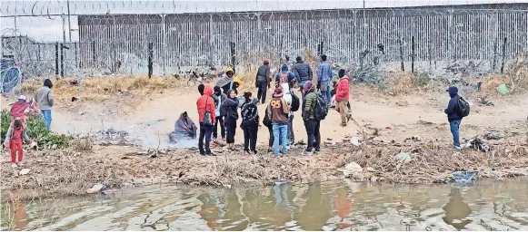  ?? ?? GRUPOS DE migrantes permanecen en el bordo estadounid­ense en espera de poder entregarse a la autoridad federal mientras elementos de la Guardia Nacional de Texas resguardan la zona