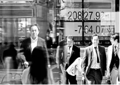  ??  ?? People walk past an electronic board showing Japan’s Nikkei average outside a brokerage in Tokyo, March 23. As US President Donald Trump dealt a blow to China with plans to slap tariffs on US$60 billion of trade, he quietly delivered a slap in the face...