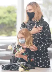  ??  ?? Sara Coffey and her daughter Emily of Wethersfie­ld hold their hands over their hearts during the 9/11 ceremony in Westport. Coffey lost her brother David Winton on Sept. 11, 2001.