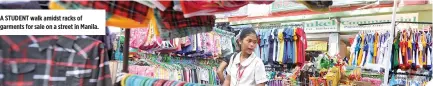  ??  ?? A STUDENT walk amidst racks of garments for sale on a street in Manila.