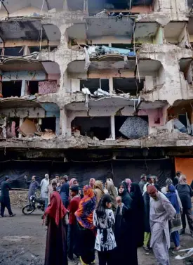  ?? AFP ?? RESIDENTS gather in front of their damaged homes at the site of a bomb blast in Karachi on March 4, the day following the attack.