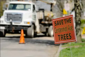  ?? Annie Ma/Post-Gazette ?? A sign urges that the century-old shade trees along Centennial Avenue in Sewickley be preserved as the removal of the trees occurs In the background.