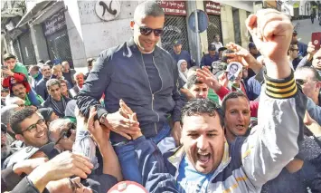  ?? — AFP photo ?? Algerian protesters carry Drareni on their shoulders after he was briefly detained by security forces in the Algerian capital Algiers.