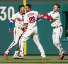  ?? LAURENCE KESTERSON — THE ASSOCIATED PRESS ?? The Phillies’ Aaron Altherr, center, is mobbed by J.P. Crawford, left, and Andrew Knapp after hitting a walk-off single in the 11th inning of a 3-2 victory over the Pirates Sunday.