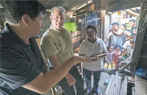  ?? Jensen Walker/Paramount Pictures photos ?? Al Gore, center, with former Mayor of Tacloban City, Alfred Romualdez, and Typhoon Haiyan survivor Demi Raya, in the Raya family home.