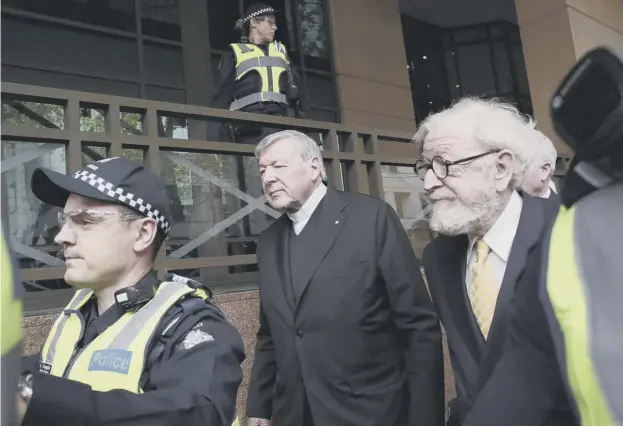  ??  ?? Australia’s highest-ranking Catholic Cardinal George Pell, centre, is escorted by police officers yesterday as he leaves the Melbourne Magistrate­s Court