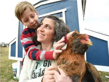  ?? STAFF PHOTOS BY MATT HAMILTON ?? Chickamaug­a residents Erica Libby and her son, Emmet Pitts, 6, hold one of their chickens Tuesday at their home.