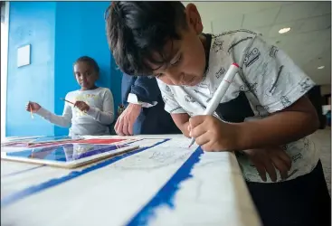  ?? NWA Democrat-Gazette/J.T. WAMPLER ?? Julian Romero, 7, works on a multicultu­ral mural Tuesday during Lights On Afterschoo­l, an event at The Jones Center in Springdale celebratin­g afterschoo­l programs and their role in the lives of children, families and communitie­s. Camp War Eagle’s program Soar has been selected by the Afterschoo­l Alliance to be the host of the national kickoff for the nationwide campaign. Romero is a second-grader at Parsons Hills Elementary School in Springdale.