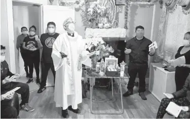  ?? JOHN MINCHILLO/AP 2020 ?? The Rev. Fabian Arias performs an in-home service last May beside the remains of Raul Luis Lopez in the Corona neighborho­od of the Queens borough of New York. Lopez died last April from COVID-19.