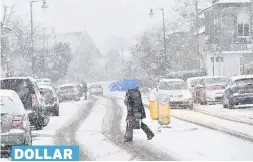  ??  ?? PILING UP A pedestrian with a brolly crosses the road as the snow descends DOLLAR