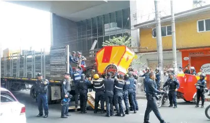  ??  ?? Policías suben a un camión uno de los mototaxis incautados que fueron utilizados para bloquear calles.