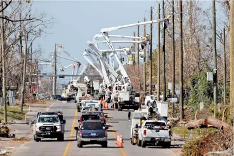  ?? AP PHOTO/GERALD HERBERT ?? Utility crews set up new poles and utility wires last week in the aftermath of Hurricane Michael in Panama City, Fla.