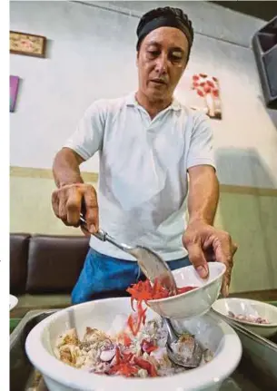  ?? (Foto Khairull Azry Bidin / BH ) ?? Jemandan menunjukka­n cara di restoranny­a, di Penampang. menyediaka­n makanan tradisi "Hinava"