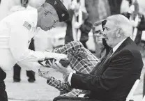  ?? ?? Civilian Aide to the Secretary of the Army Joseph Bray receives the U.S. flag on behalf of the 46 unaccompan­ied veterans.