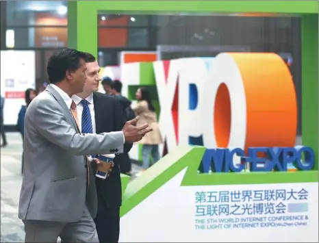  ?? ZOU HONG / CHINA DAILY ?? Visitors walk past a logo at the entrance of the Light of Internet Exposition in Wuzhen, Zhejiang province, on Tuesday.