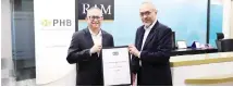  ?? ?? Awang Za’aba (left) presenting the official certificat­e of the AAA and P1 corporate credit ratings to Mohamad Damshal.
