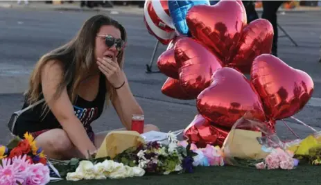  ?? MARK RALSTON/AFP/GETTY IMAGES ?? Destiny Alvers, who attended the Route 91 country music festival and helped rescue her friend who was shot, cries at a makeshift memorial.