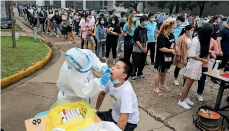  ?? AFP ?? Mass tEst: a medical worker takes a swab sample from a man to be tested for coronaviru­s in Wuhan on Friday. nervous residents of China’s pandemic epicentre of Wuhan queued up across the city to be tested for virus after a new cluster of cases sparked a mass screening campaign. —