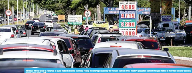  ?? —AFP ?? BRASILIA: Drivers queue to pump fuel at a gas station in Brasilia, on Friday. Fearing fuel shortage caused by the truckers’ national strike, Brasilia’s population rushed to the gas stations to fuel their cars and face long queues across town.