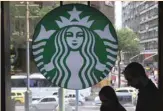  ?? — Reuters ?? Customers pass by the logo of an American coffee company Starbucks inside a coffee shop in Rio de Janeiro, Brazil.