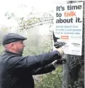  ??  ?? Steven Pollock puts up anti-suicide signs at Cave Hill country park