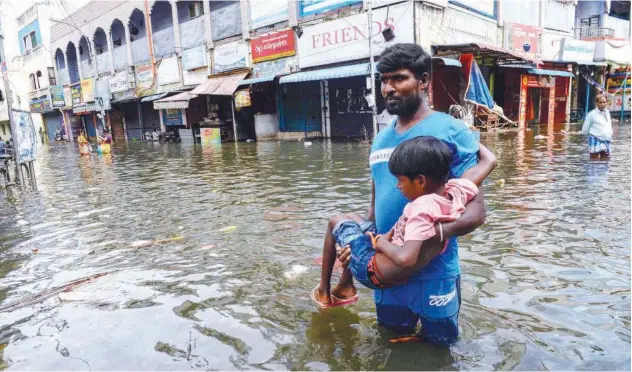  ?? Agence France-presse ?? ↑
People wade through a waterlogge­d street in a residentia­l area after heavy rain in Chennai on Friday.