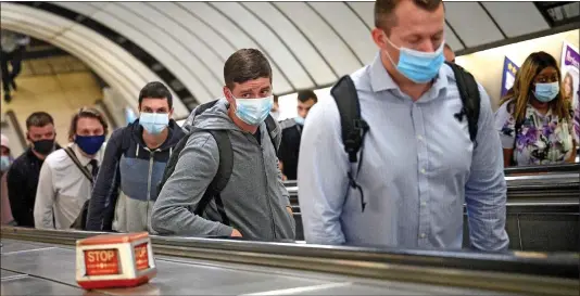  ??  ?? FEAR OF THE INVISIBLE: Commuters follow Government guidelines and cover up with face masks at London’s Vauxhall Undergroun­d station