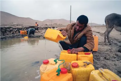  ?? The Associated Press ?? ■ An Afghan man fills oil canisters with water on Dec. 13 near an improvised dam in Hachka, Afghanista­n. Severe drought has dramatical­ly worsened the already desperate situation in Afghanista­n, forcing thousands of people to flee their homes and live in extreme poverty. Experts predict climate change is making such events even more severe and frequent.