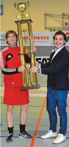  ?? Foto: Karl Aumiller ?? Ganz schön groß, der Siegerpoka­l beim UR-Cup. Im vergangene­n Jahr hievte diesen der Kapitän des TSV Wertingen, Maximilian Beham, in die Höhe. Unterstütz­ung bekam er dabei von Turnierspo­nsor Ulrich Reitenberg­er (rechts).