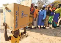  ?? TSVANGIRAY­I MUKWAZHI AP FILE ?? A child carries a parcel from the U.N. World Food Program in Mwenezi, Zimbabwe. The WFP has won the 2020 Nobel Peace Prize for its efforts to combat hunger around the globe.