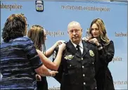  ?? DISPATCH ERIC ALBRECHT / THE COLUMBUS ?? Interim Columbus Police Chief Thomas Quilan has his daughters, Cassie, 15, and Mackenzie, 22, right, add stars to his uniform while wife, Jennifer, watches after his swearing in ceremony Friday.