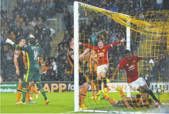  ?? Mark Runnacles / Getty Images ?? Manchester United’s Marcus Rashford (19) scores the game-winner as Wayne Rooney (10) celebrates and Hull goalkeeper Eldin Jakupovic (left) throws up his arms in frustratio­n.