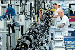  ?? AP/JENS MEYER ?? Workers assemble engines on a Volkswagen Sachsen production line in Chemnitz, Germany, in June. Volkswagen Sachsen is a subsidiary of Volkswagen AG.