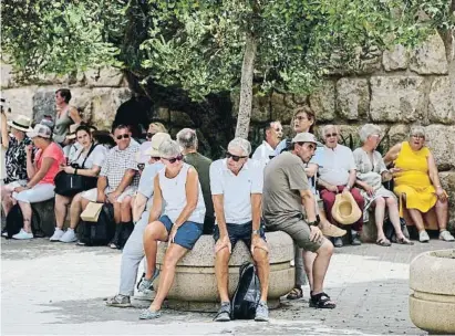  ?? Barce oaneF e sts ?? Uns turistes descansen asseguts a l’ombra a la vora dels Reales Alcázares de Sevilla