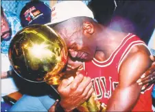  ?? Ken Levine / TNS ?? The Chicago Bulls’ Michael Jordan sits nexts to his wife Juanita and his dad James while hugging the NBA Championsh­ip Trophy after the Bulls defeated the Los Angeles Lakers 4-1 after Game 5 of the NBA Finals in 1991 at the Great Western Forum in Inglewood, Calif.